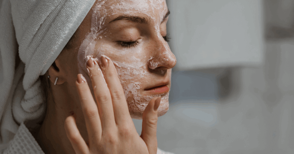 An image of a woman applying a clay face mask