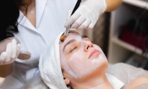 Beautician applying facial to woman's face in spa