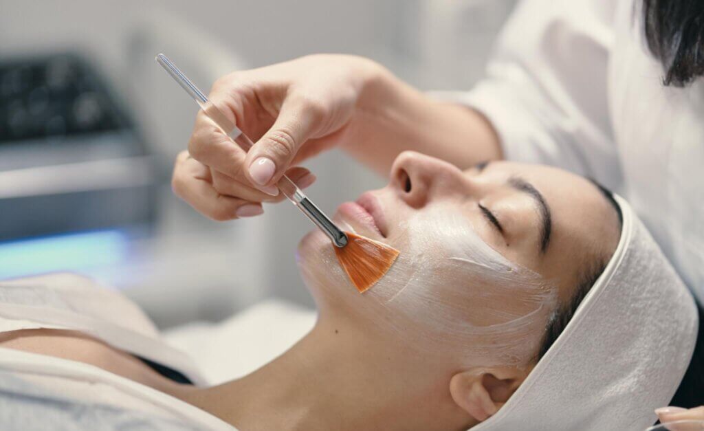 Beautician applying facial to woman's face in spa