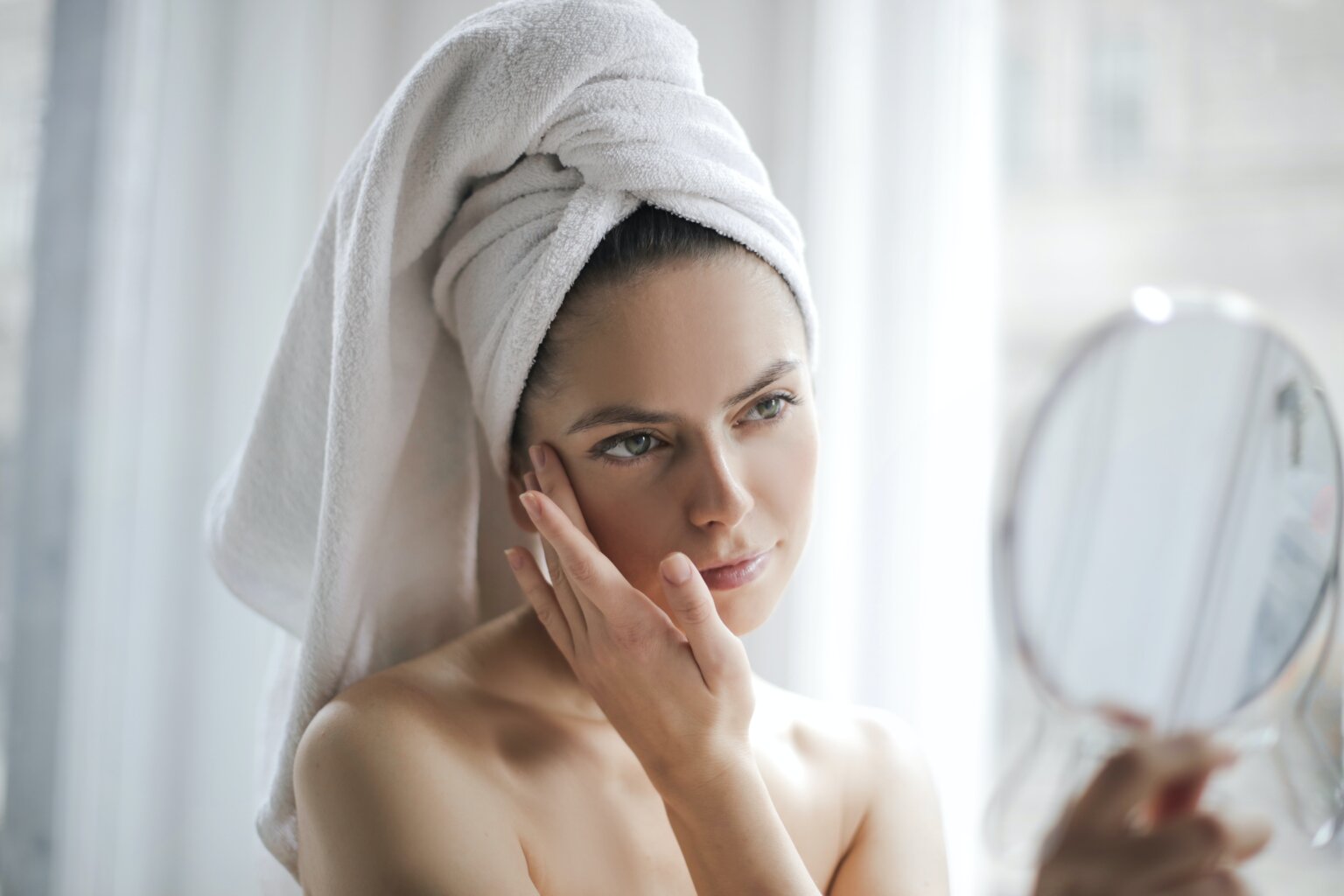 Woman looking in mirror at acne scars