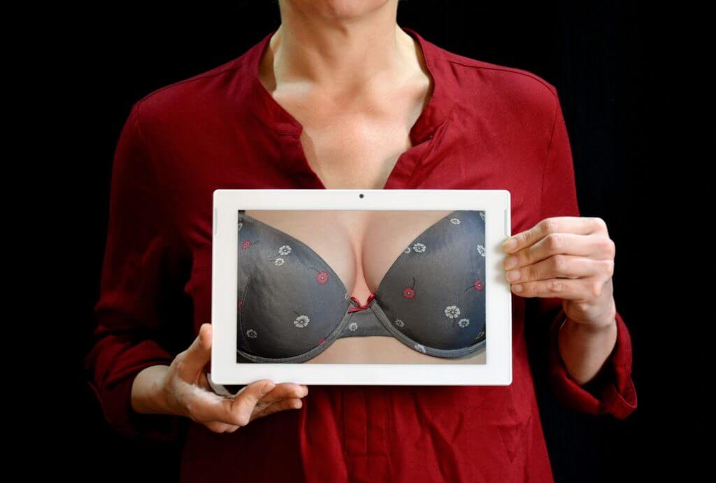 Woman holding picture of breasts with black bra
