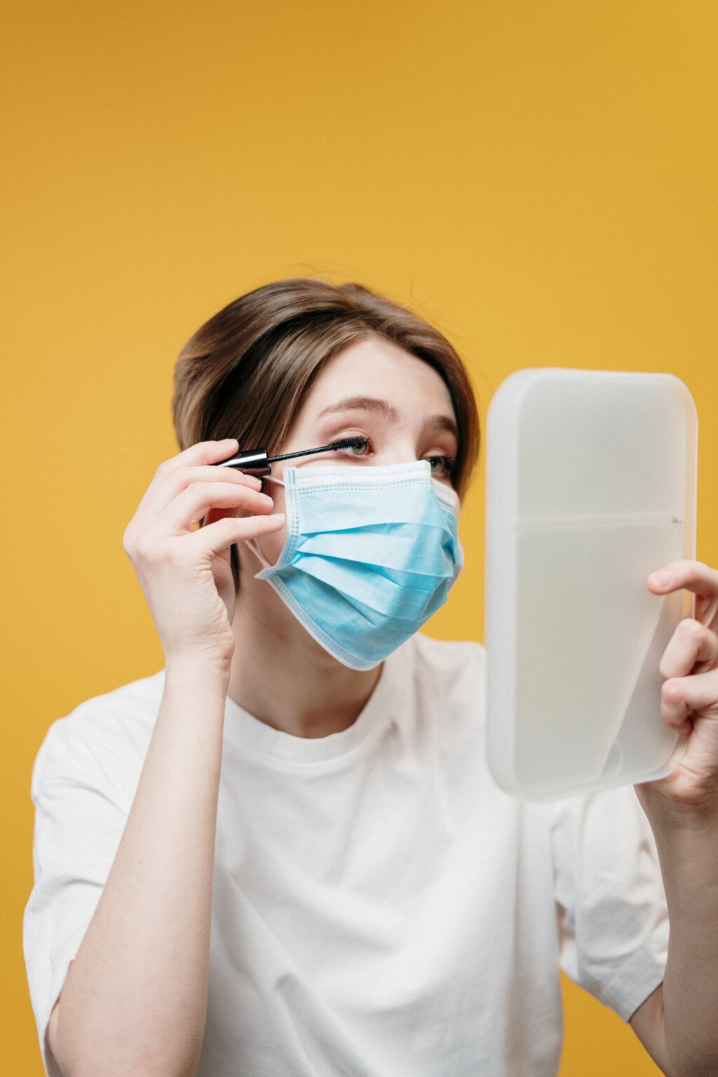 woman in white with mask putting on make up