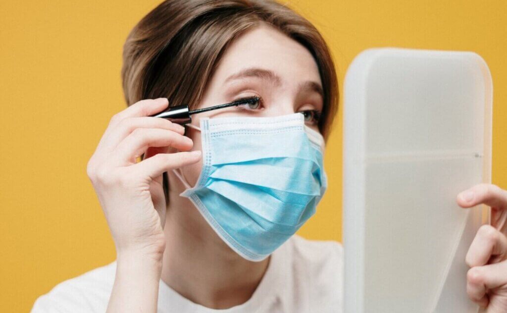 woman in white with mask putting on make up