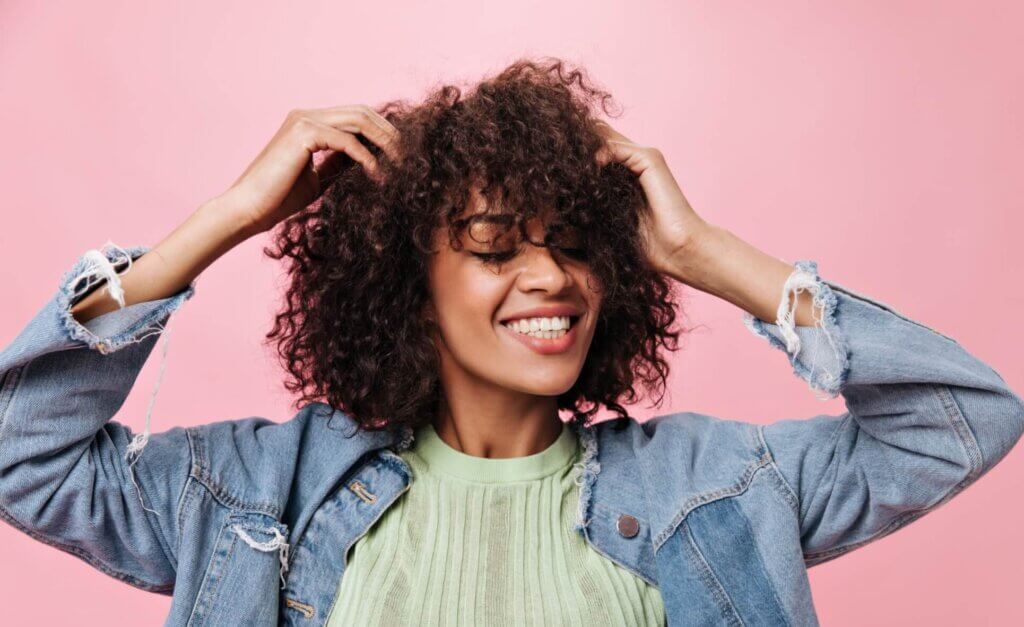 How to Maintain Curly and Afro Hair: 10 Hair Care Tips For You Woman playing with her curly hair